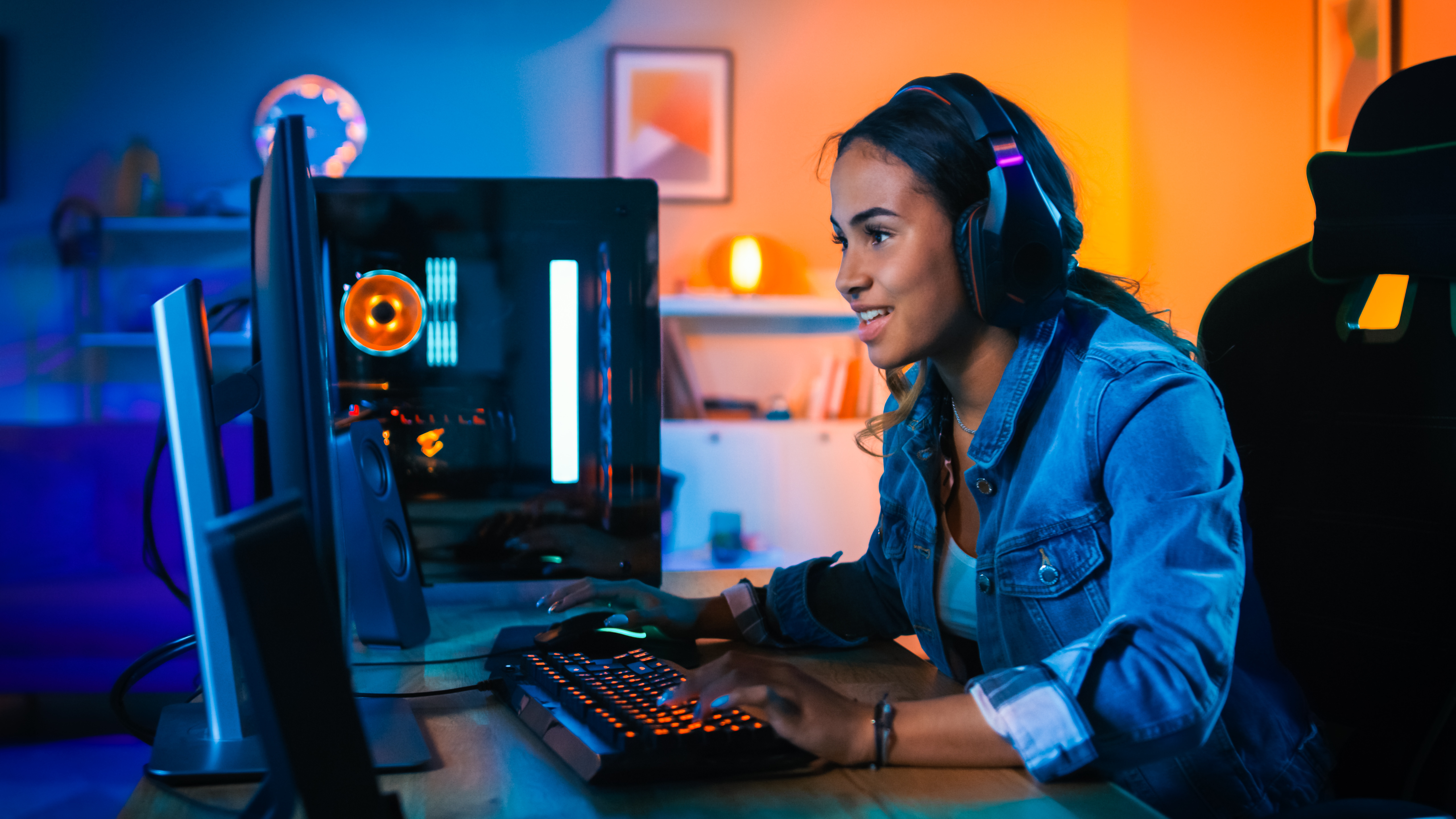 Happy looking gamer sat at a desktop monitor on a desk